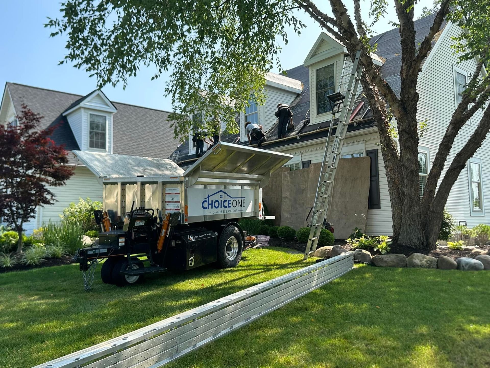 Choice One Restoration crew replacing a roof in Northeast Ohio with branded equipment on site